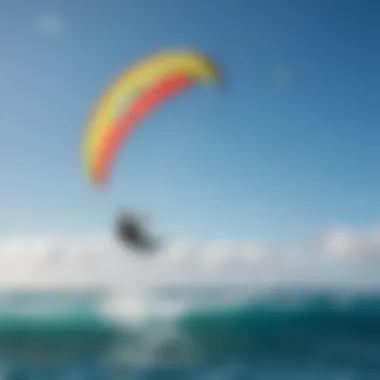 Kiteboarder gliding over the waves with vibrant kite colors against a blue sky