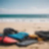 A variety of kitesurfing equipment laid out on a beach